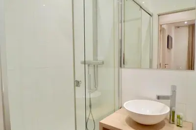 a bathroom with a sink and a glass shower at Appartements Urban et Pure in Cannes