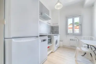 a white kitchen with a table and a refrigerator at IMMOGROOM - Appartment - 1min from the beach - Wifi in Cannes