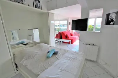 a white bedroom with a bed and a red chair at Nice apartment last floor with terrace and clear view on the sea in Cannes