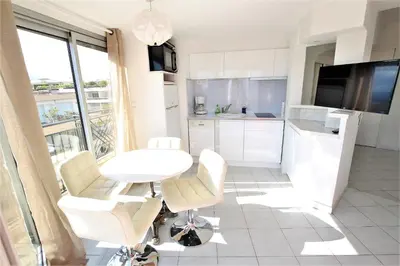 a white kitchen with a white table and chairs at Nice apartment last floor with terrace and clear view on the sea in Cannes