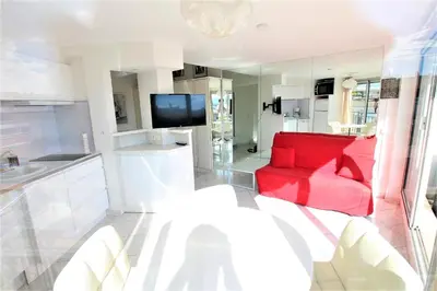 a living room with a red couch and a tv at Nice apartment last floor with terrace and clear view on the sea in Cannes
