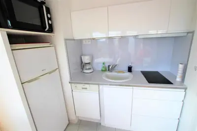 a small white kitchen with a sink and a microwave at Nice apartment last floor with terrace and clear view on the sea in Cannes