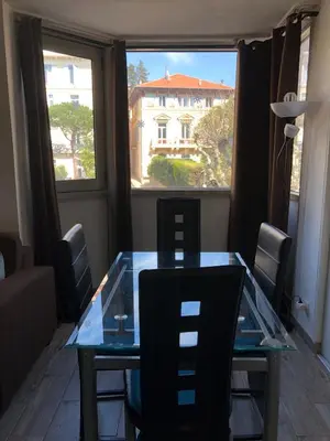 a glass table and chairs in a room with a large window at Vacances Cannoise, mer et piscine in Cannes