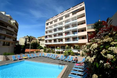 a hotel with a swimming pool and chairs and a building at Vacances Cannoise, mer et piscine in Cannes