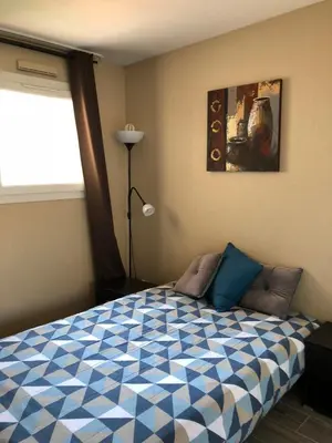 a bedroom with a blue and white bed with a window at Vacances Cannoise, mer et piscine in Cannes