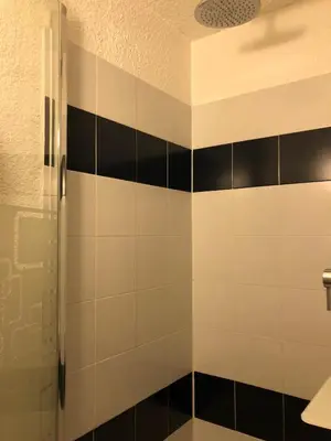 a bathroom with black and white tiled walls and a shower at Vacances Cannoise, mer et piscine in Cannes