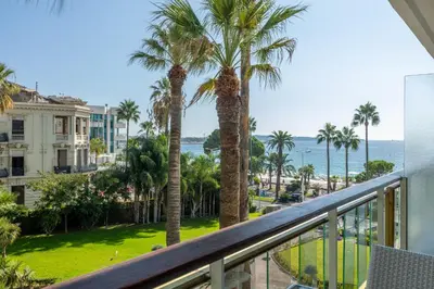 a balcony with palm trees and the ocean at Agence des Résidences - Appartements privés du 45 CROISETTE - Standard in Cannes