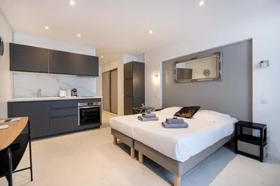 a bedroom with a large bed and a kitchen at Agence des Résidences - Appartements privés du 45 CROISETTE - Standard in Cannes