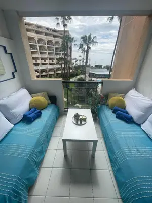 a room with two beds and a table on a balcony at Sea view La Palme d'Azur apartment steps away from the beach and perfect for holidays & business trips in Cannes