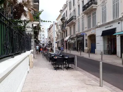 a city street with tables and chairs on a sidewalk at Croisette carre d'or in Cannes