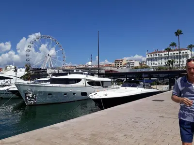 a man is standing next to a marina with boats at Croisette carre d'or in Cannes