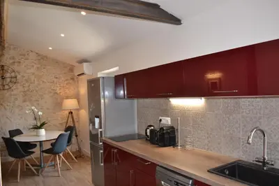a kitchen with red cabinets and a table with chairs at 2 pièces Vagliano in Cannes