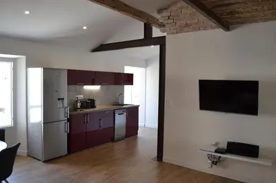 a kitchen with wooden floors and a tv on the wall at 2 pièces Vagliano in Cannes