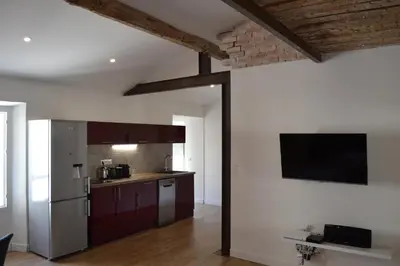 a kitchen with a refrigerator and a tv on the wall at 2 pièces Vagliano in Cannes