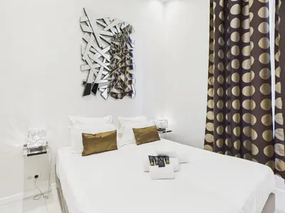 a white bedroom with a white bed with gold pillows at Residence du Louvre - Apartments - Prime location Palais & Croisette - Luxury Stay by LRA Cannes in Cannes