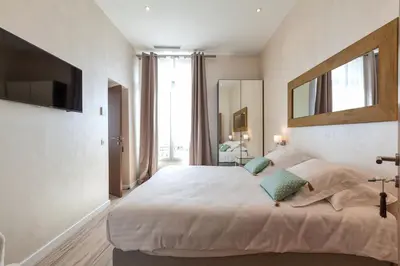 a bedroom with a large white bed with a large window at Residence du Louvre - Apartments - Prime location Palais & Croisette - Luxury Stay by LRA Cannes in Cannes