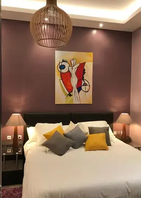 a bedroom with a bed with a painting on the wall at NUMA BLANC 300 M PALAIS DES FESTIVALS in Cannes