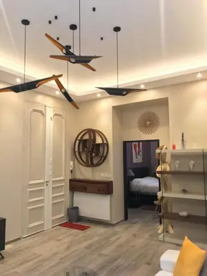 a living room with a ceiling fan and a bedroom at NUMA BLANC 300 M PALAIS DES FESTIVALS in Cannes