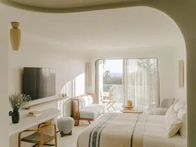 a white bedroom with a bed and a window at Hôtel & Spa Belle Plage in Cannes
