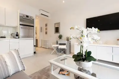 a white living room with a tv and a table at PALAIS MIRAMAR CROISETTE APART 1 MIN CARLTON in Cannes