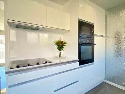a kitchen with white cabinets and a vase of flowers at Luxury 