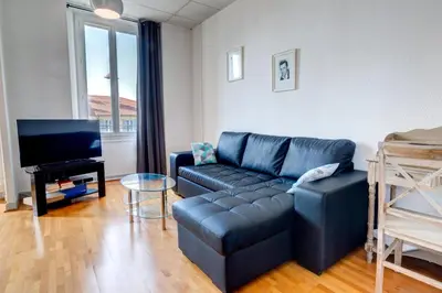 a living room with a black leather couch and a tv at IMMOGROOM - Charming apartment - City Center - Wifi - AC in Cannes