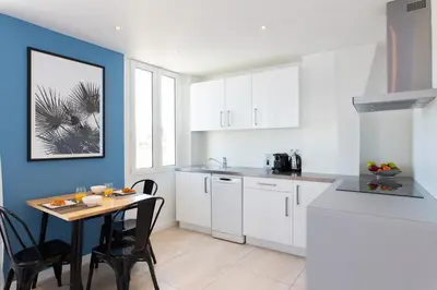 a kitchen with white cabinets and a table with chairs at Maracuja YourHostHelper in Cannes