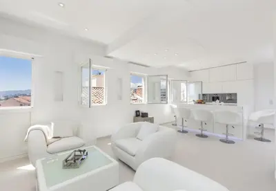 a white living room with white chairs and a table at Hôtel Traverse Des Artistes in Cannes
