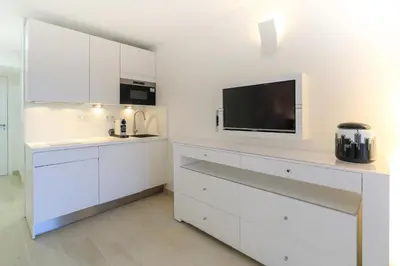 a kitchen with white cabinets and a flat screen tv at Hôtel Traverse Des Artistes in Cannes