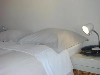 a white bed with pillows and a lamp on a night stand at ACCI Cannes Les Yuccas in Cannes
