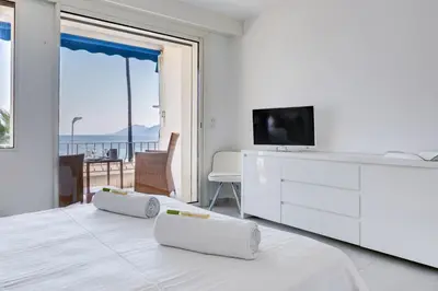 a white bedroom with a tv and a bed with two pillows at IMMOGROOM - 3 Sea view Panoramic terrace - 1 min beach - CONGRESSBEACH in Cannes