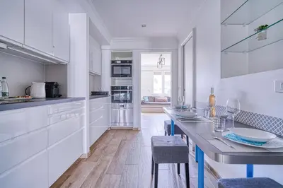 a kitchen with white cabinets and a table with chairs at Le Marignan in Cannes