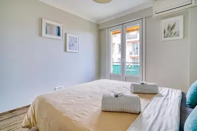 a white bedroom with a bed and a window at Le Marignan in Cannes
