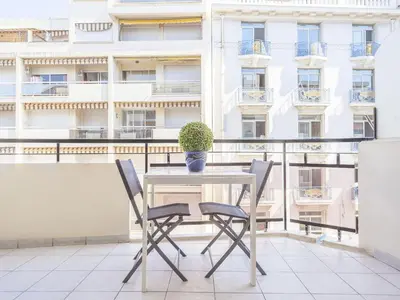 a table and chairs on a balcony with a building at Lovely One bedroom Martinez Cannes in Cannes