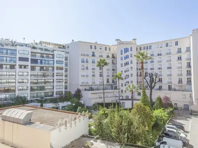 a view of a building with palm trees and buildings at Lovely One bedroom Martinez Cannes in Cannes