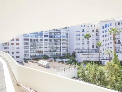 a large white building with palm trees in front of it at Lovely One bedroom Martinez Cannes in Cannes