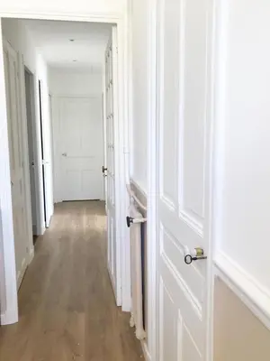 an empty hallway with white doors and wooden floors at les néfliers in Cannes