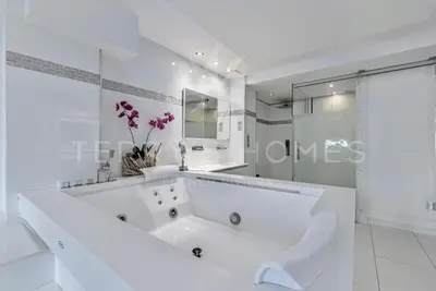 a white bathroom with a large tub and a shower at Appartement l'Age d'Or in Cannes