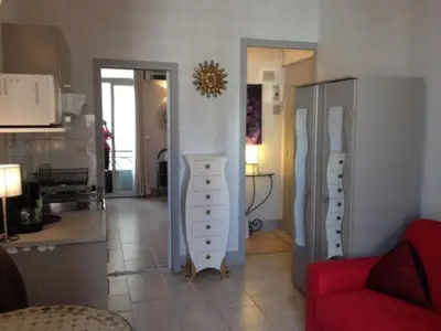 a living room with a red couch and a kitchen at Studio Cannes Croisette in Cannes