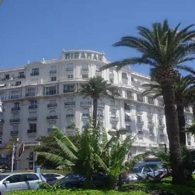 a large white building with palm trees in front of it at Studio Cannes Croisette in Cannes