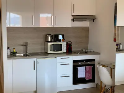 a kitchen with white cabinets and a microwave at La Goelette - Palais des Festivals in Cannes