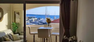 a living room with a table and a view of a harbor at La Goelette - Palais des Festivals in Cannes