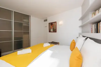 a bedroom with a large white bed with yellow accents at Mer du Sud 4 YourHostHelper in Cannes