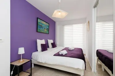a purple bedroom with a bed and a purple wall at Mer du Sud 4 YourHostHelper in Cannes