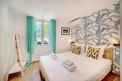 a bedroom with a large white bed with blue curtains at IMMOGROOM - Sea view apartment - 3 min from beach - AC in Cannes