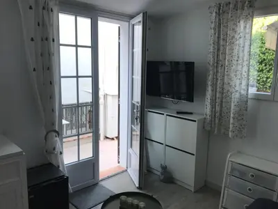 a living room with a television and a sliding glass door at Les fleurs in Cannes
