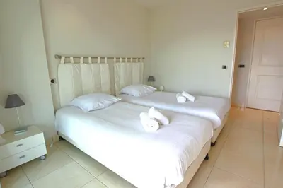 two beds in a bedroom with white sheets and towels at Fully equipped apartment with large terrace lounge area in Cannes