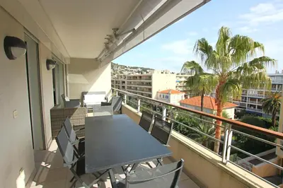 a balcony with a table and chairs and a palm tree at Fully equipped apartment with large terrace lounge area in Cannes