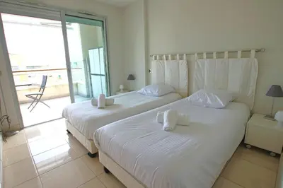 two beds in a bedroom with a view of the ocean at Fully equipped apartment with large terrace lounge area in Cannes