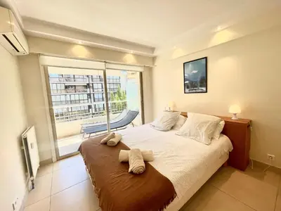 a bedroom with a large bed and a large window at Branly by Welcome to Cannes in Cannes